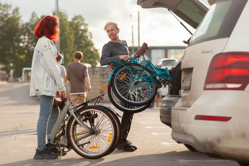 Велосипед складывают в багажник автомобиля